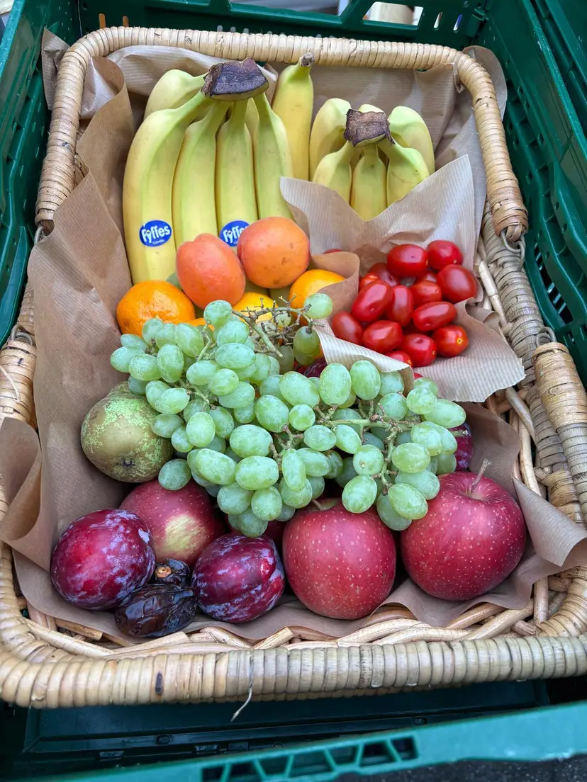 Een mand met bananen, druiven, appels en pruimen
